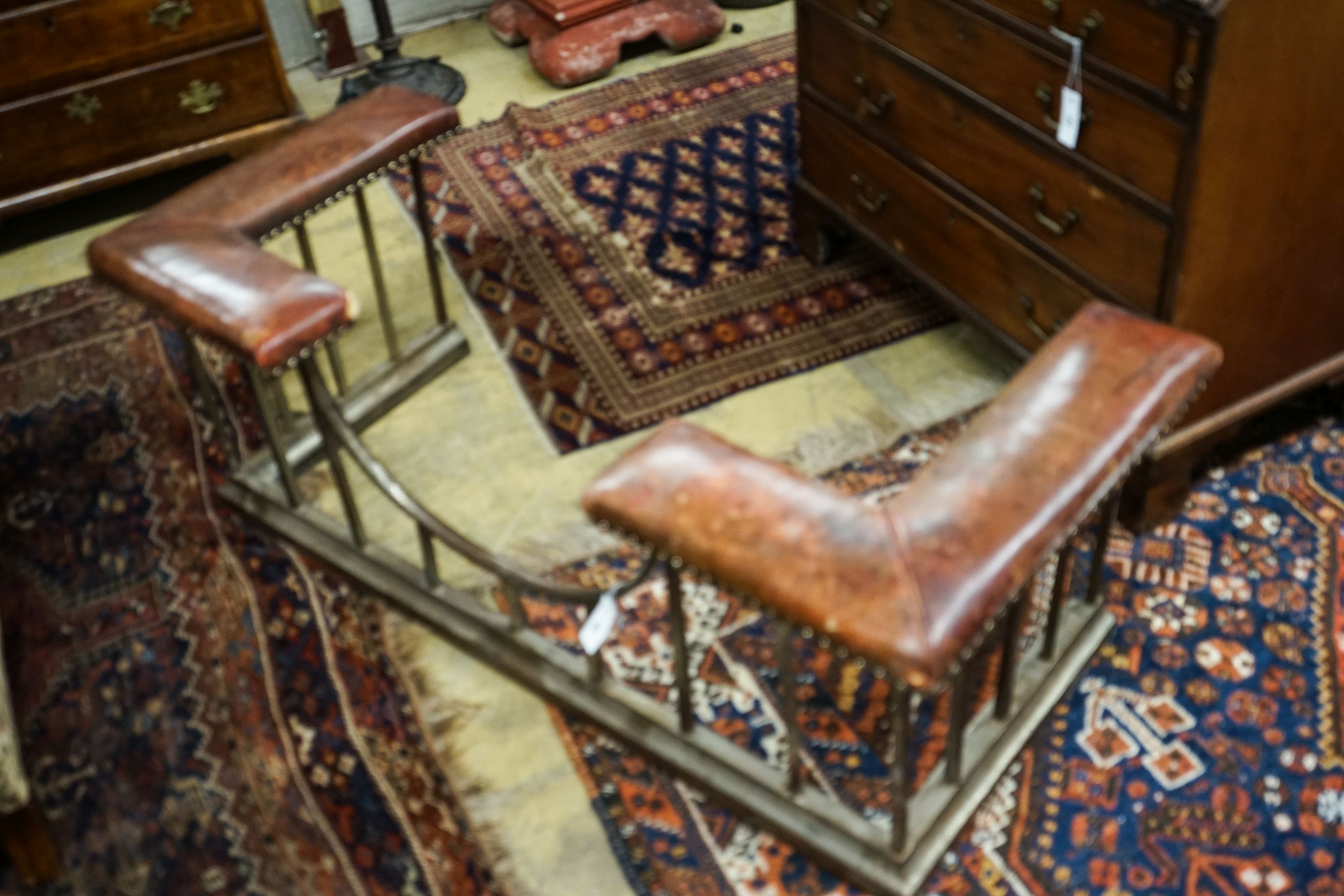 An early 20th century steel and burgundy leather club fender, length 140cm, depth 58cm, height 50cm